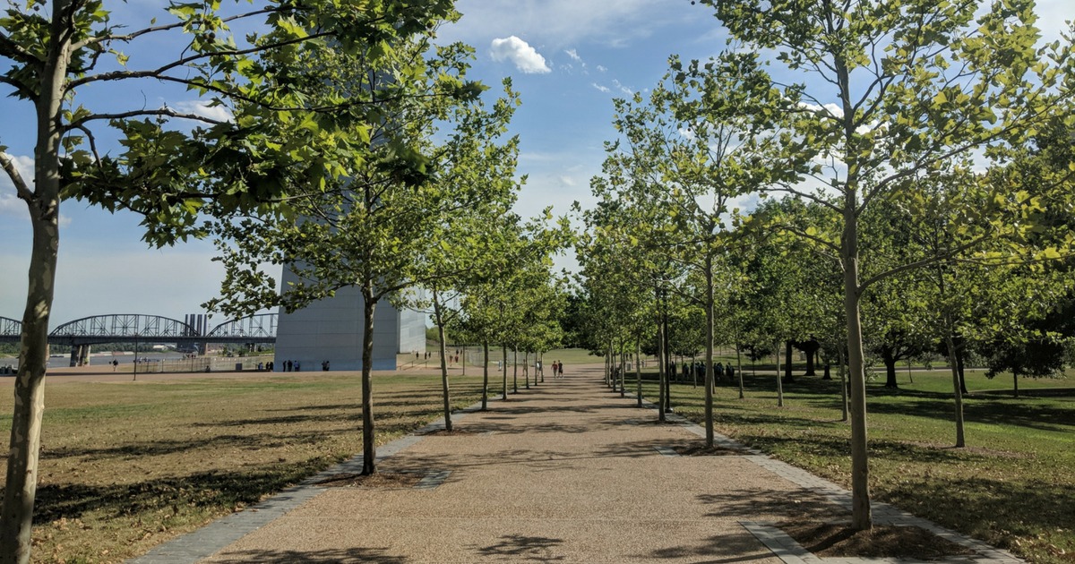 Walking toward the Gateway Arch with trees along the path